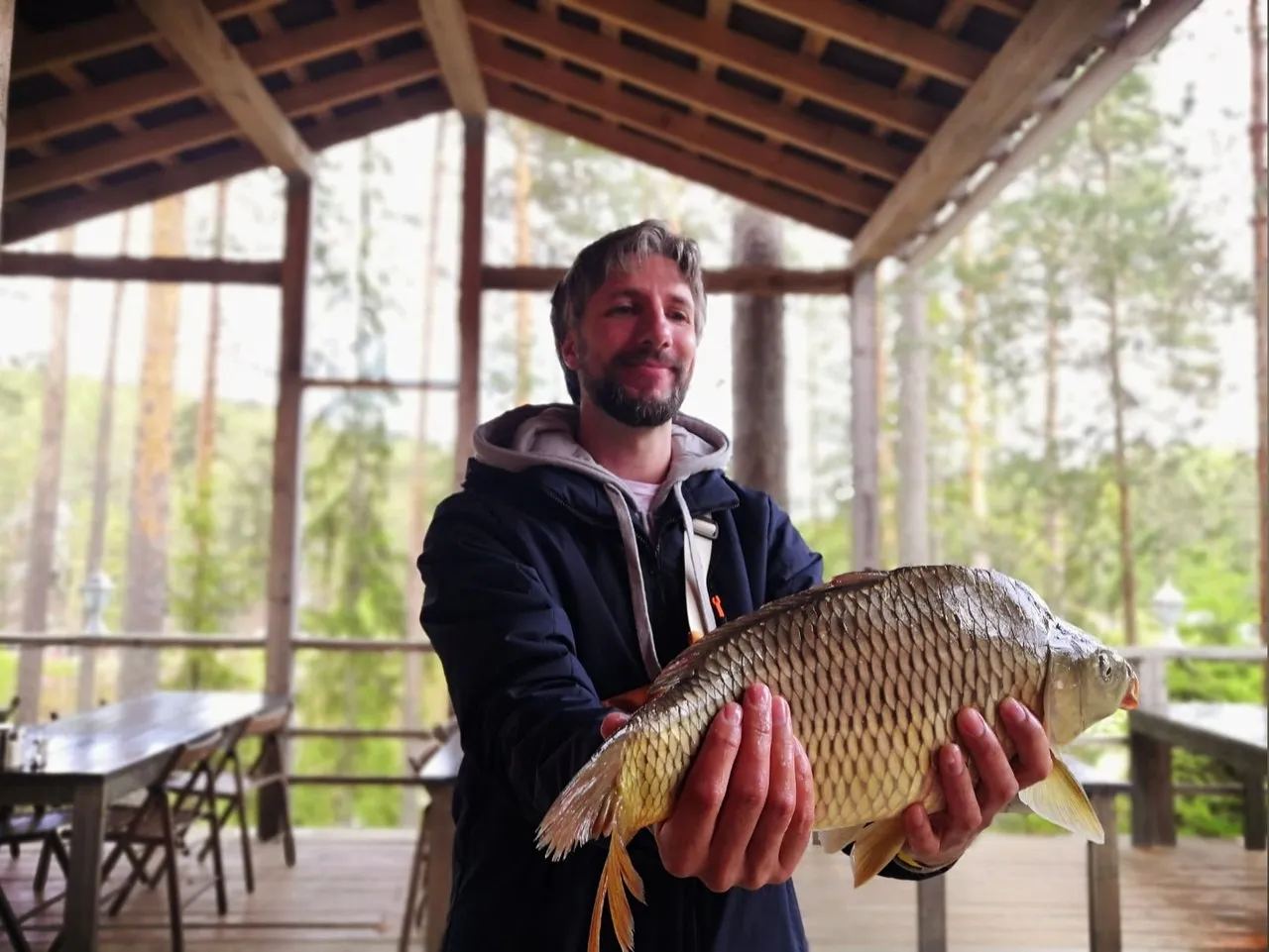 Рыбак на мостках у зарыбленного озера GREENVALD Fishing в парке Скандинавия