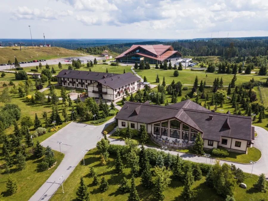 Панорама всесезонного курорта Игора зимой с освещенными горнолыжными трассами, подъемниками, отелем и коттеджным поселком в снежном обрамлении