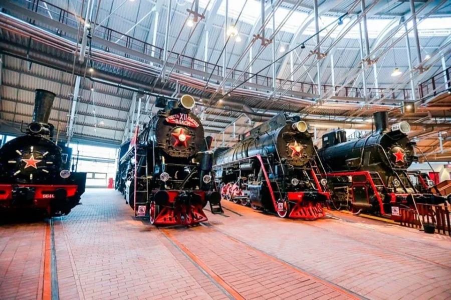 Панорамный вид на главный зал Музея железных дорог России с историческими паровозами, вагонами и интерактивными экспозициями, рассказывающими об истории железнодорожного транспорта