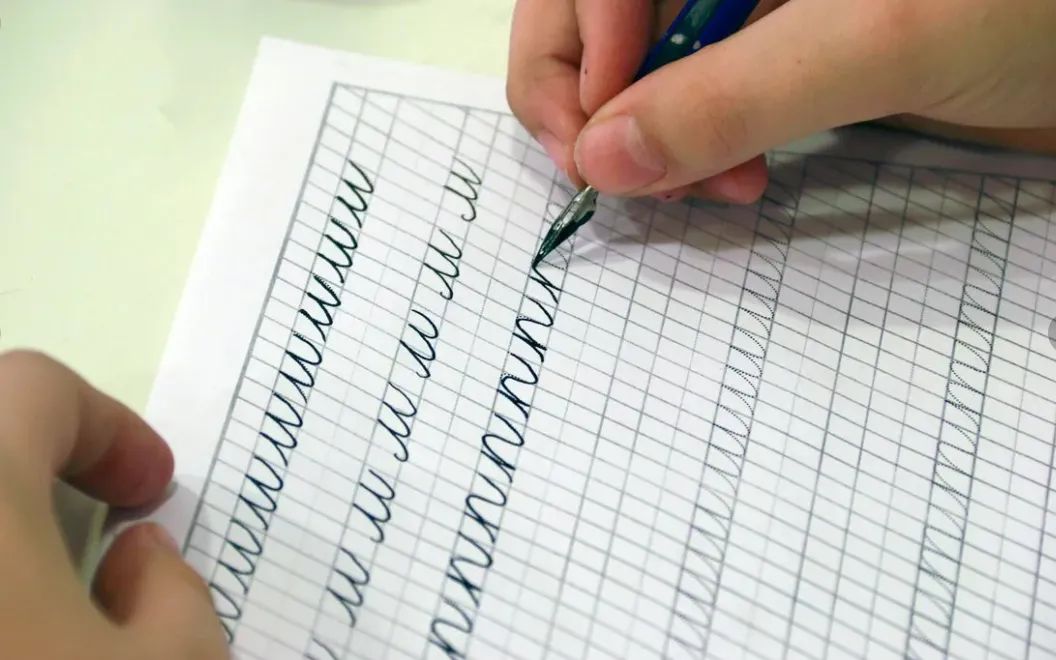 Детская рука выводит буквы в прописи на занятии каллиграфией в SmartyKids
