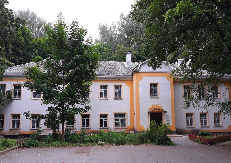 Белое деревянное здание музея-усадьбы Ганнибалов в окружении деревьев