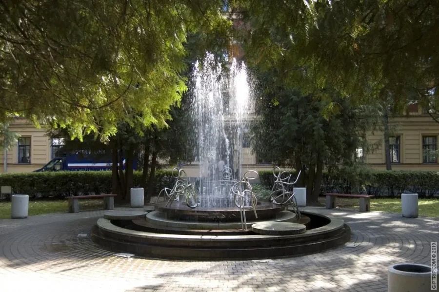 Круглый фонтан с металлическими фигурами студентов по периметру и струями воды в центре