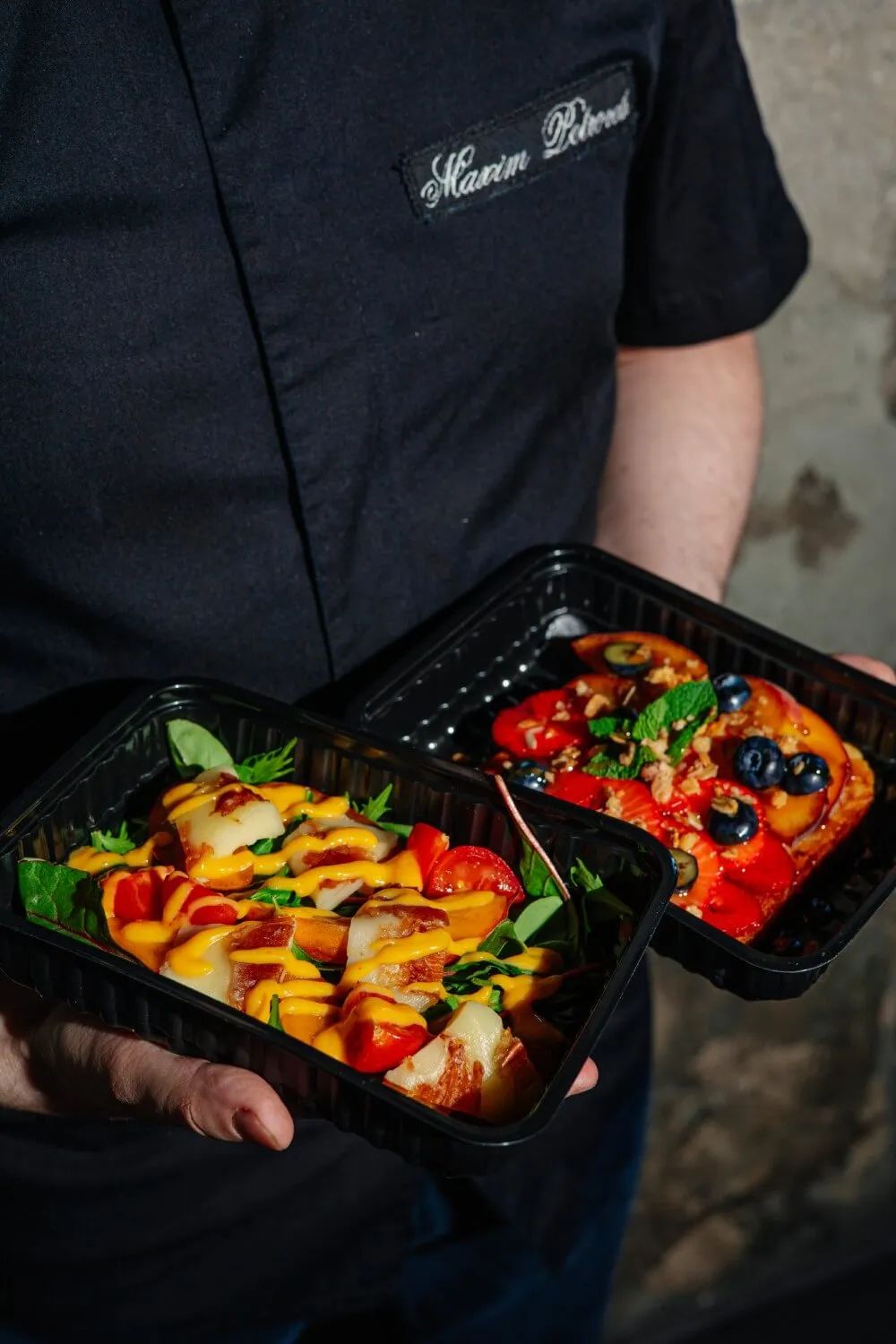 Два контейнера BlackBFood в руках курьера