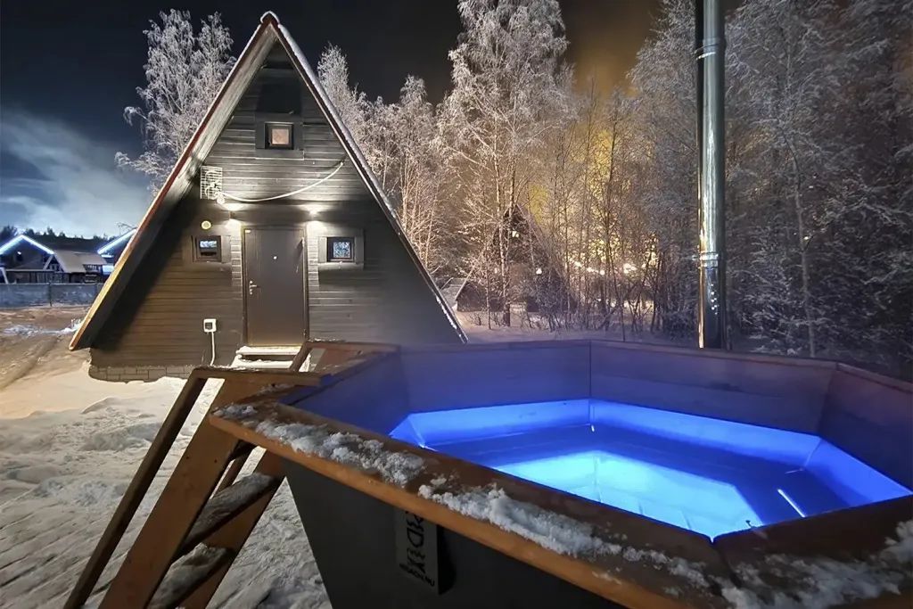 Глэмпинг A-frame Village у Красного озера — чёрный А-фрейм с подсвеченным банным чаном