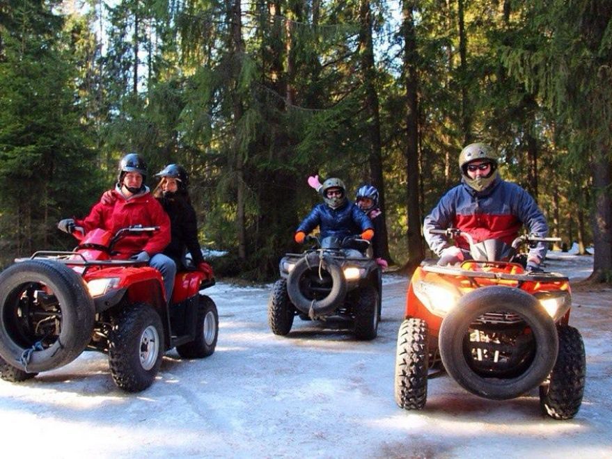 Синий квадроцикл мчится по бездорожью, преодолевая грязевой участок в лесу около Токсово