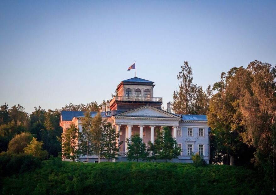 Белый деревянный особняк на холме с колоннами