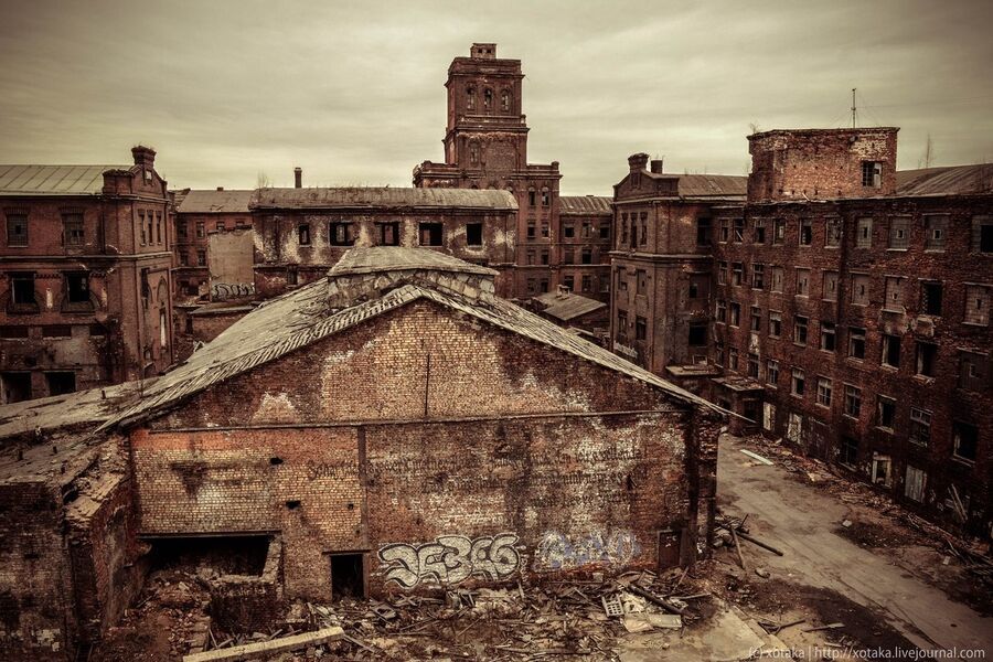 Заброшенные корпуса завода Красный треугольник с характерной индустриальной архитектурой красного кирпича и высокими трубами