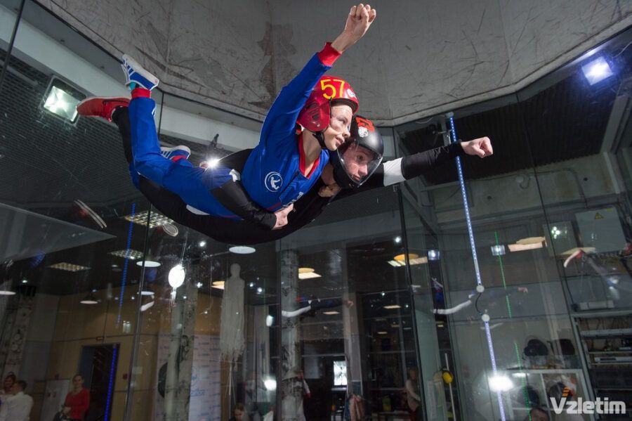 Посетитель парит в воздушном потоке аэродинамической трубы под наблюдением инструктора