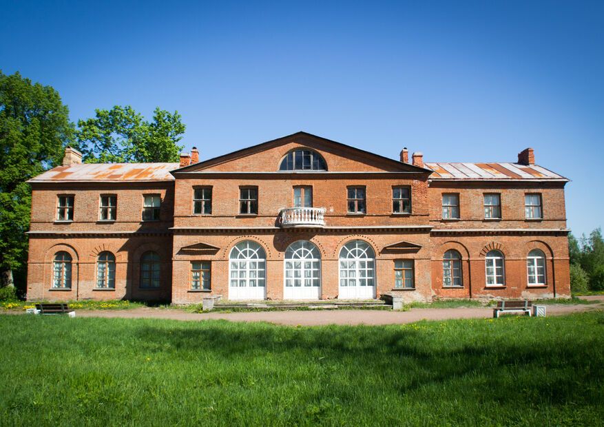 Деревянный усадебный дом с мезонином в окружении деревьев